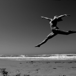 naked woman jumping on the beach