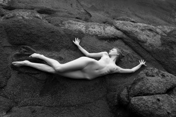 naked blond girl lying on a rock