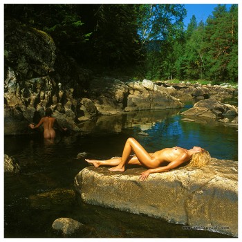 naked blonde woman lying in the sun at a lake