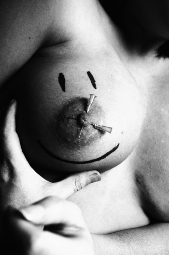 Bare breast with piercings and a smiley